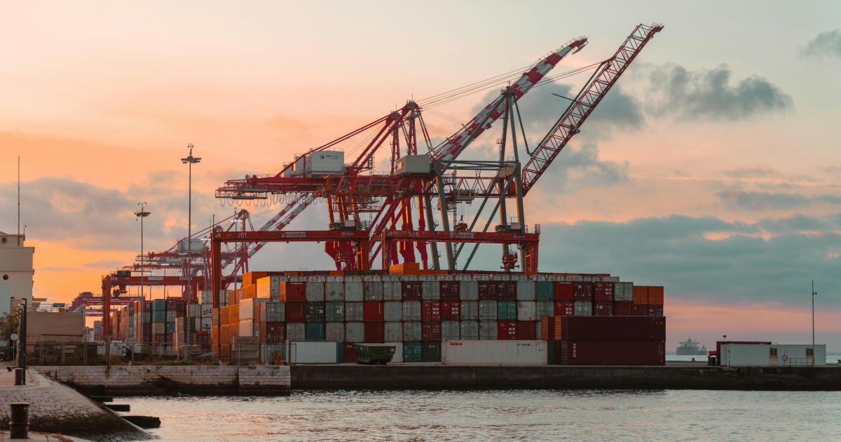 Container cranes at a bustling port during sunset