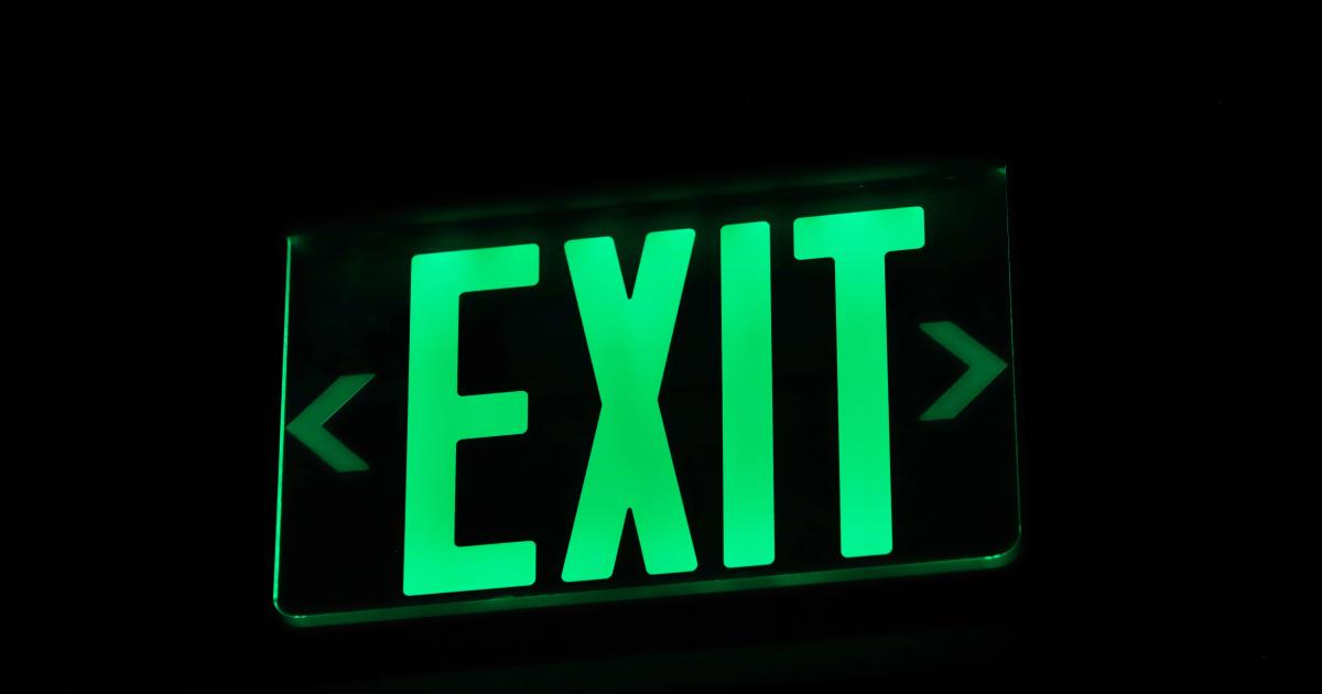 Bright green emergency exit sign illuminated in darkness — the official escape hatch