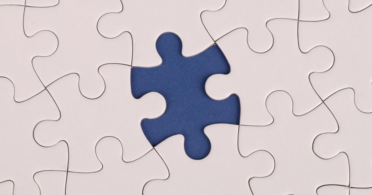 White jigsaw puzzle with one missing piece revealing a blue background
