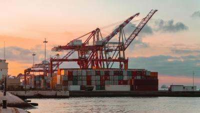 Container cranes at a bustling port during sunset