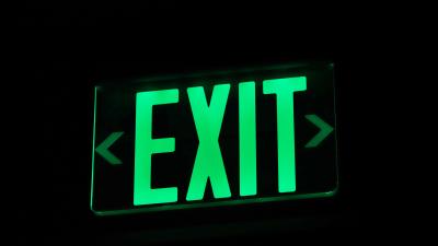 Bright green emergency exit sign illuminated in darkness — the official escape hatch
